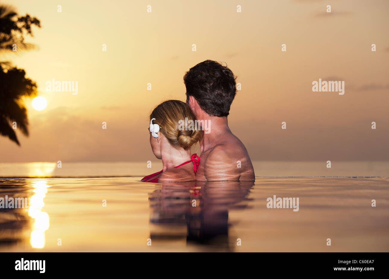 Giovane abbracciando nella piscina infinity Foto Stock