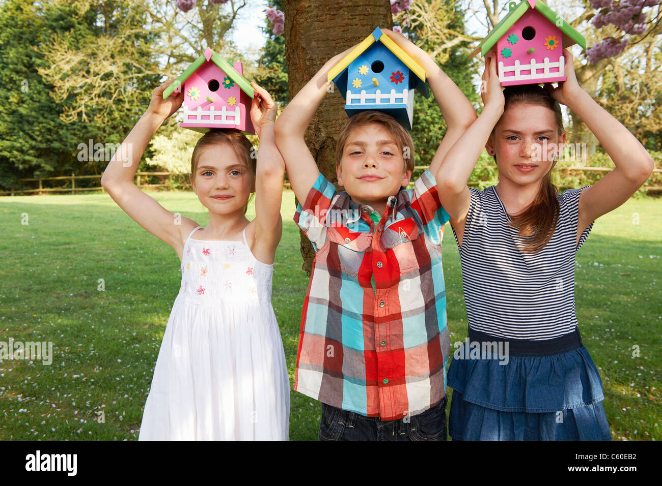 Bambini holding birdhouses in cortile Foto Stock