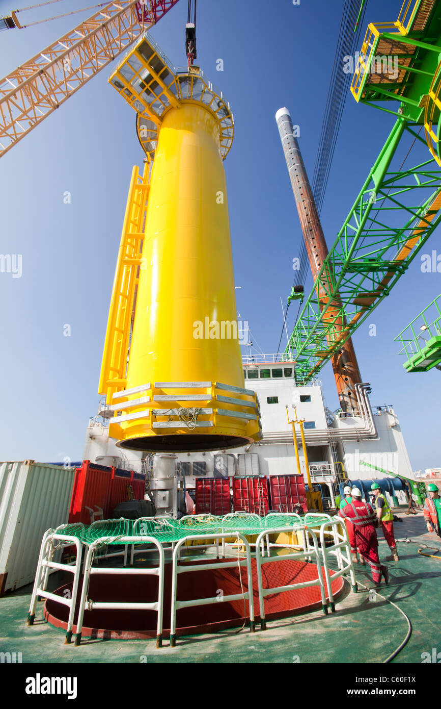 Una gru solleva un pezzo di transizione di una turbina eolica su un martinetto fino barge, pronti a costruire il Walney offshore wind farm Foto Stock