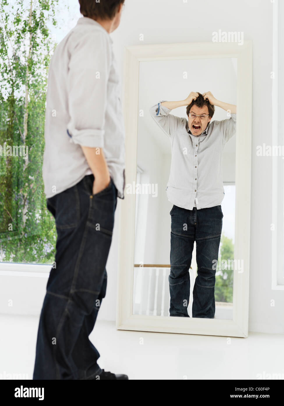 L'uomo esaminando la sua riflessione smorfie Foto Stock