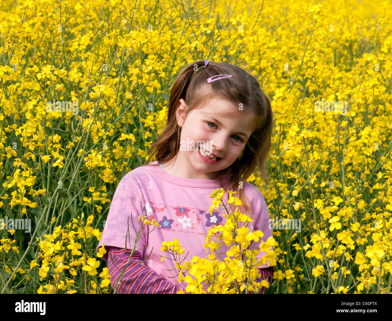 Ragazza giovane con un abito rosa in un campo di colza gialli di primavera a Chesham, Bucks, Regno Unito Foto Stock