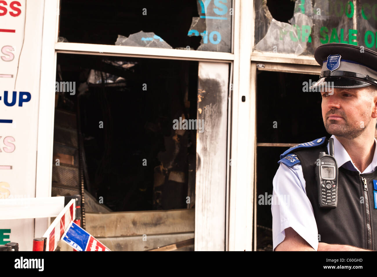 Poliziotto fuori bruciata shop in Lavender Hill, Londra In seguito al saccheggio, disordini e arson Foto Stock