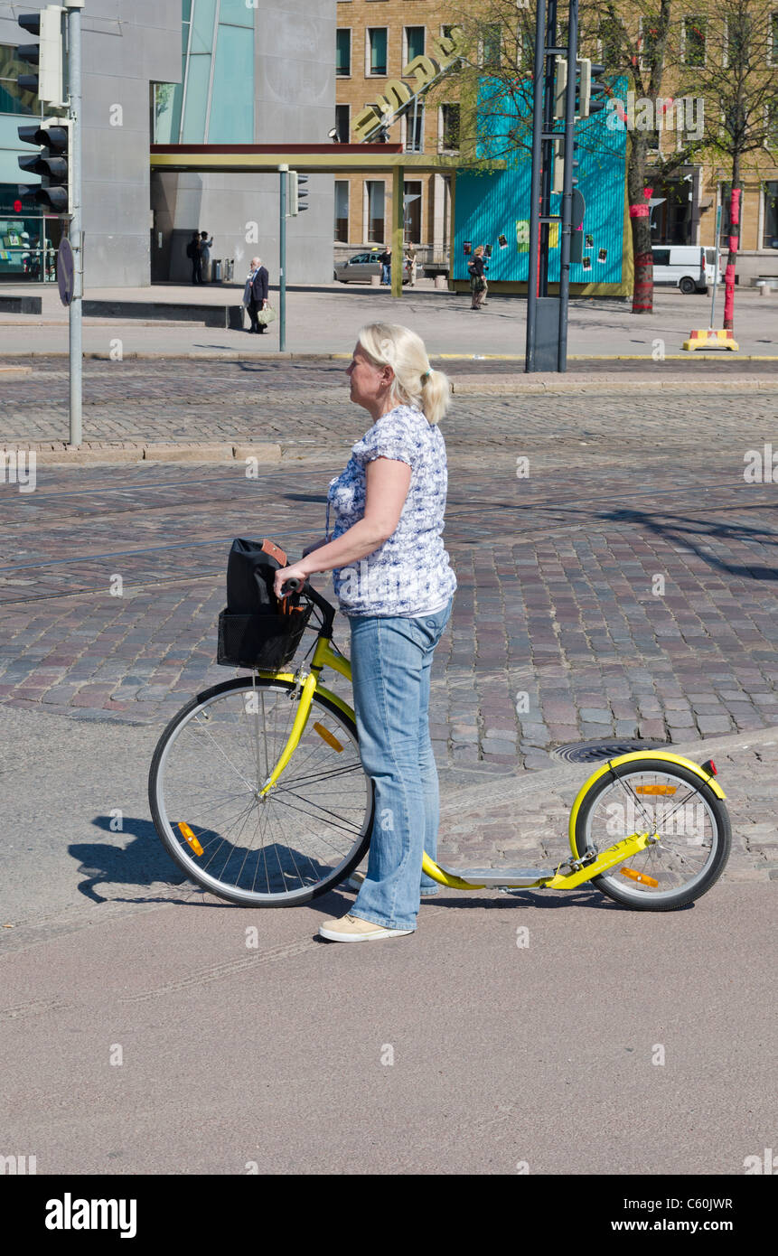 Una donna finlandese con un kick scooter a Helsinki in Finlandia Foto Stock