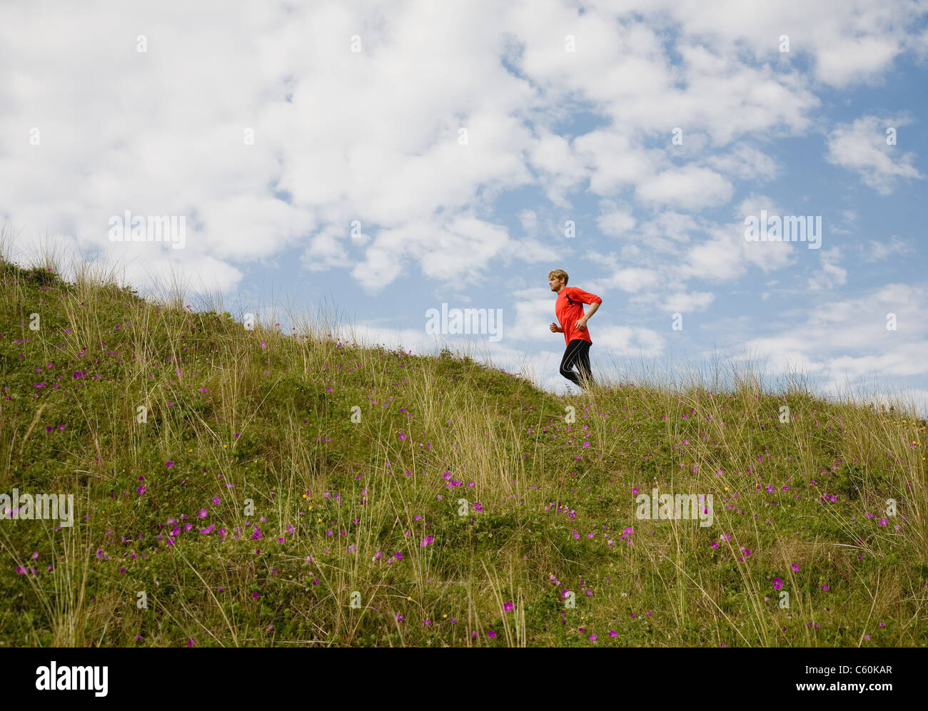 L'uomo corre su pendio erboso Foto Stock