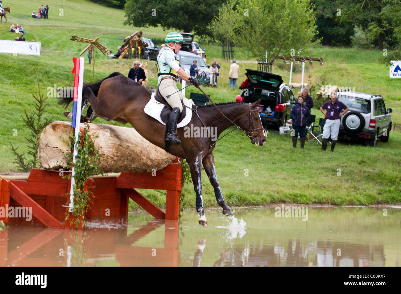 Cavallo e cavaliere saltando in acqua sulla cross-country al Festival britannico di eventing a Gatcombe Park in Gloucestershire Foto Stock