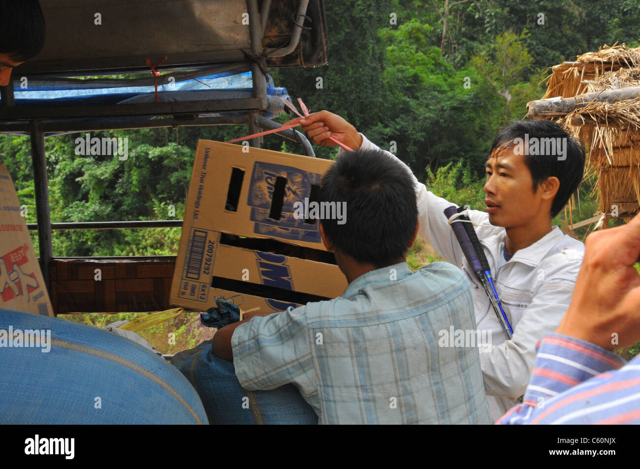 I ragazzi di scarico scatole pesanti e sacco di riso per andare al fiume Mekong Laos Foto Stock