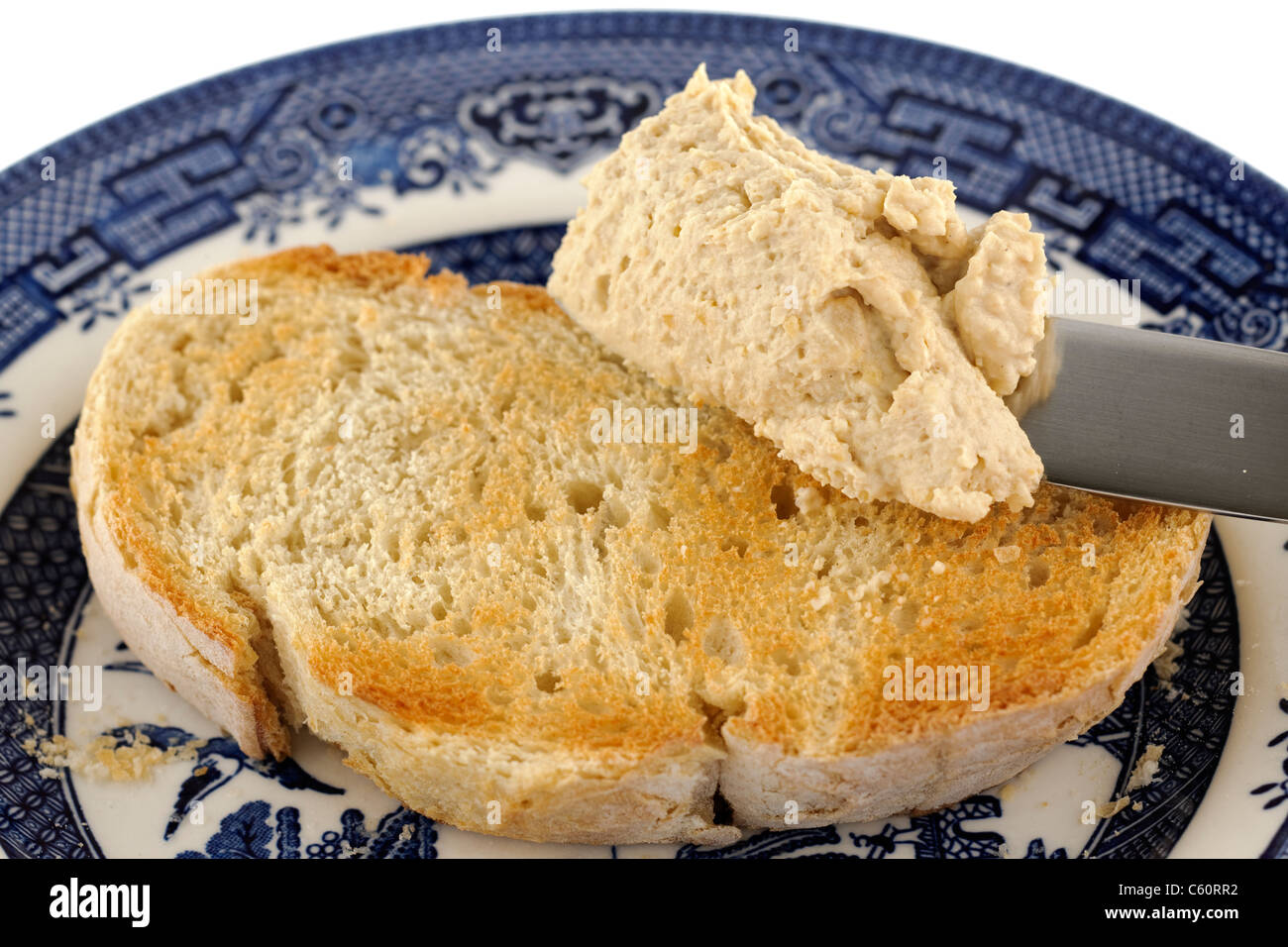 In casa di spessore hummus con aglio extra essendo diffuso su appena tostati Pane bianco Foto Stock