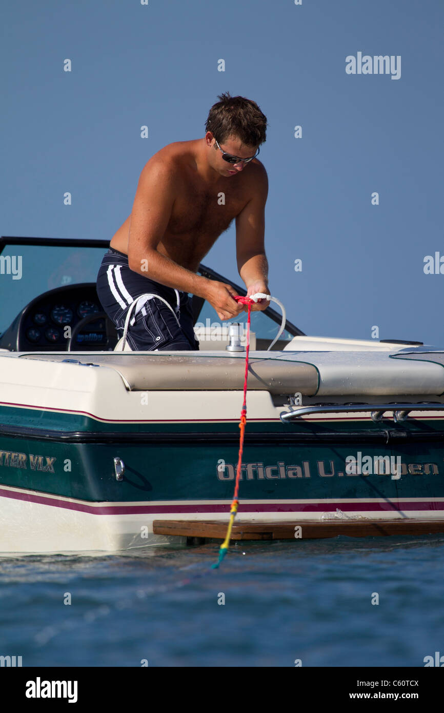 Un uomo il fissaggio di una corda di sci al traliccio su una barca di sci. Foto Stock