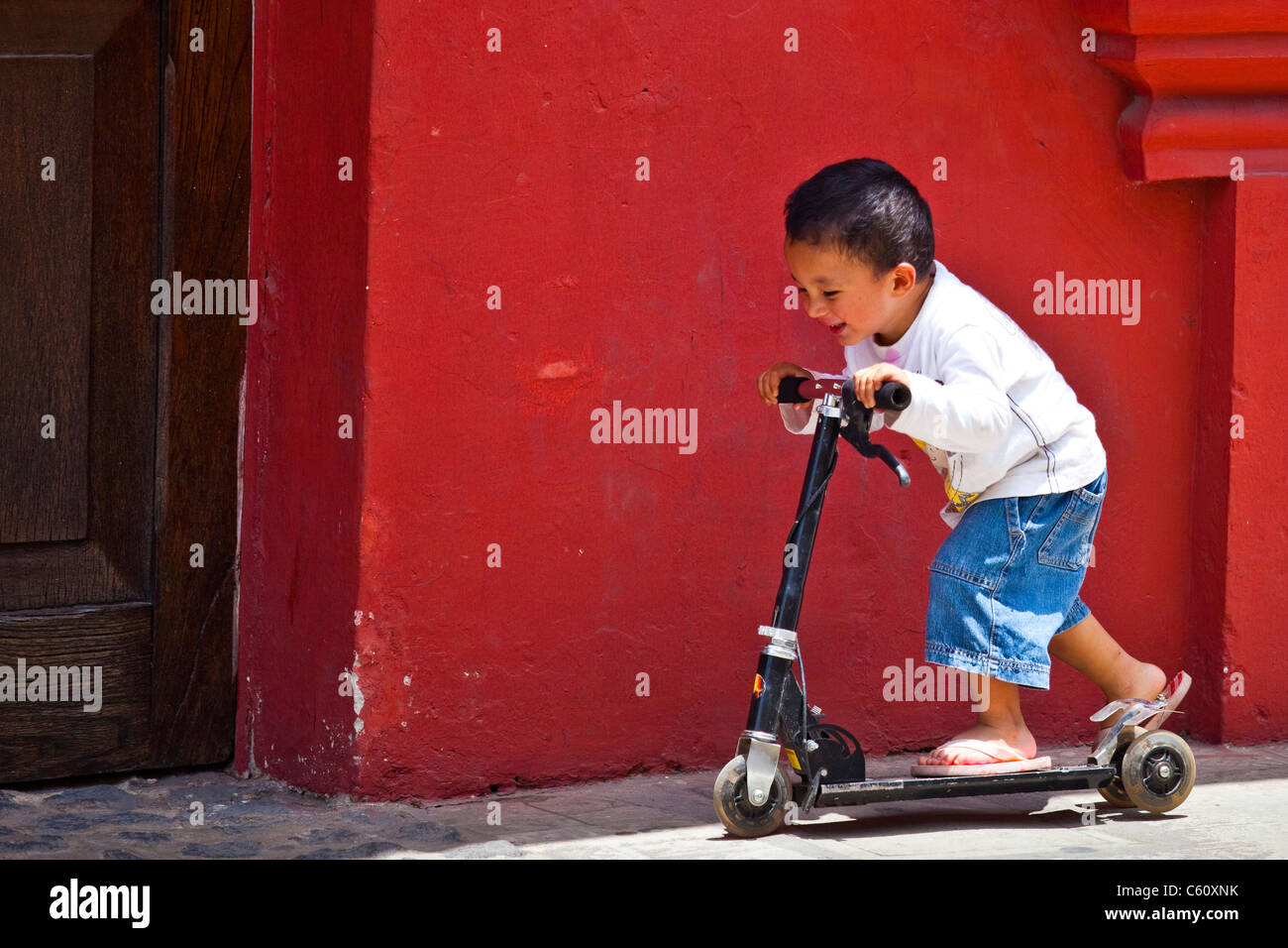 Giovane ragazzo giocando su un rasoio scooter, Antigua, Guatemala Foto Stock