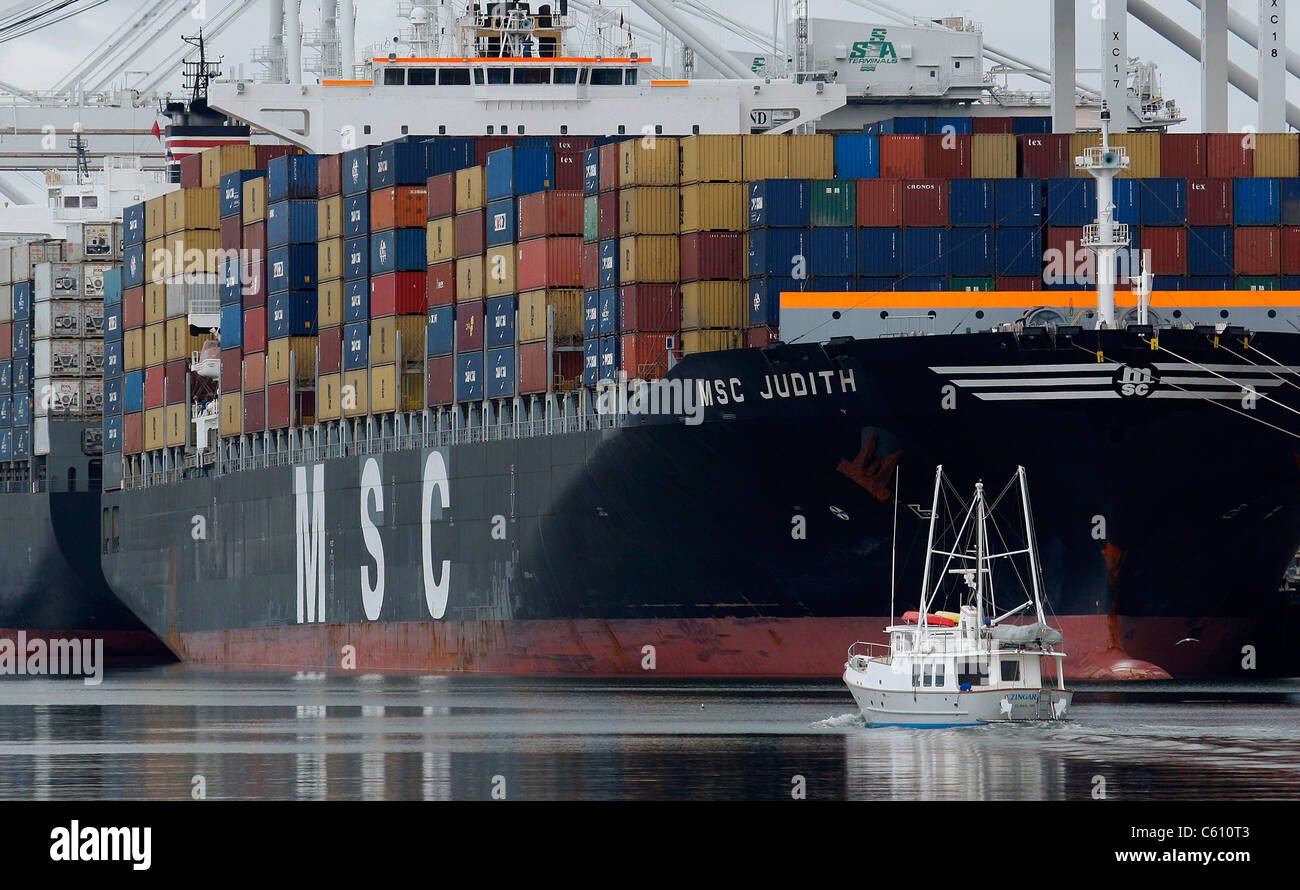 Un battello da diporto motori oltre le navi portacontainer di aspettare di essere scaricato sull'estuario di Oakland in California. Foto Stock