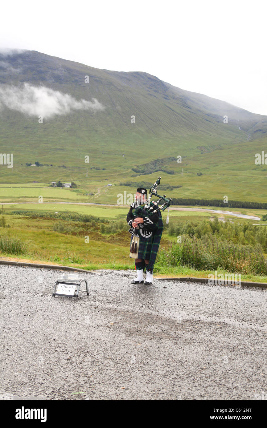 Bagpiper nelle Highlands della Scozia a giocare per denaro Foto Stock
