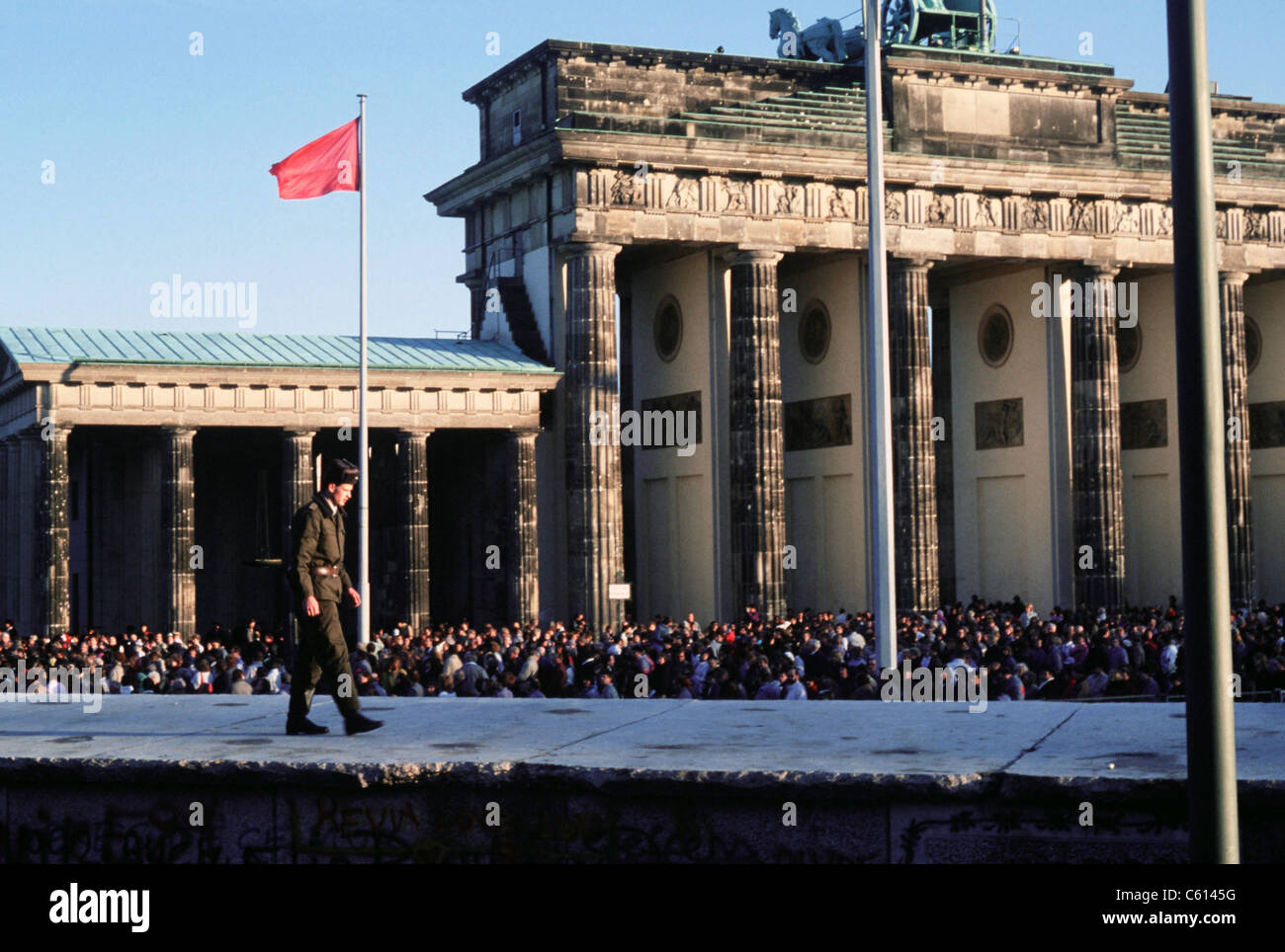 Una folla di berlinesi intorno alla Porta di Brandeburgo seguendo la struttura dell'apertura ufficiale il 22 dicembre 1989. In primo piano un tedesco orientale passeggiate di guardia sul muro di Berlino. (BSLOC_2011_3_51) Foto Stock