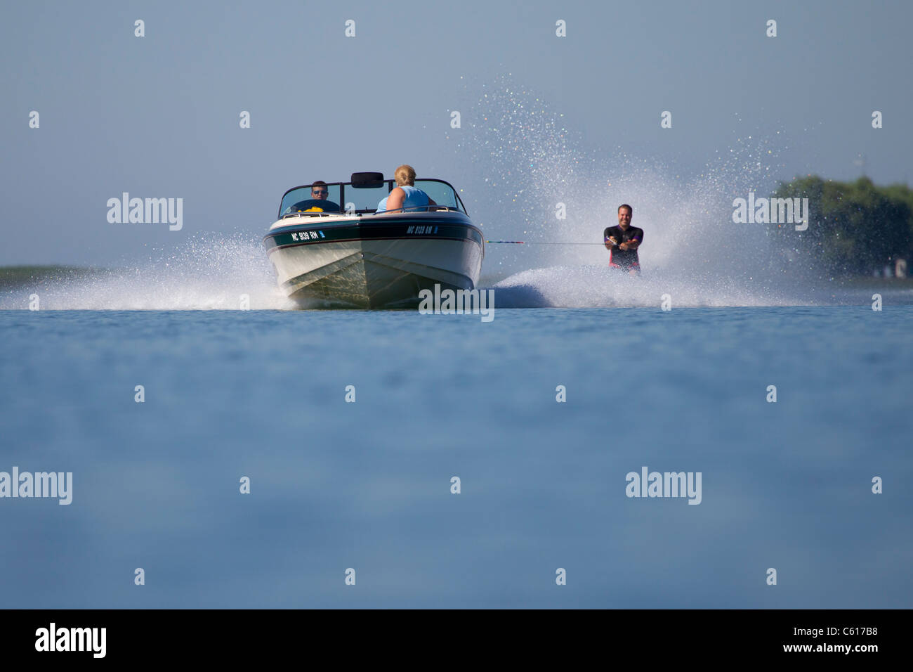 Un avvicinamento veloce barca sci tirando un waterskier a piedi nudi. Foto Stock