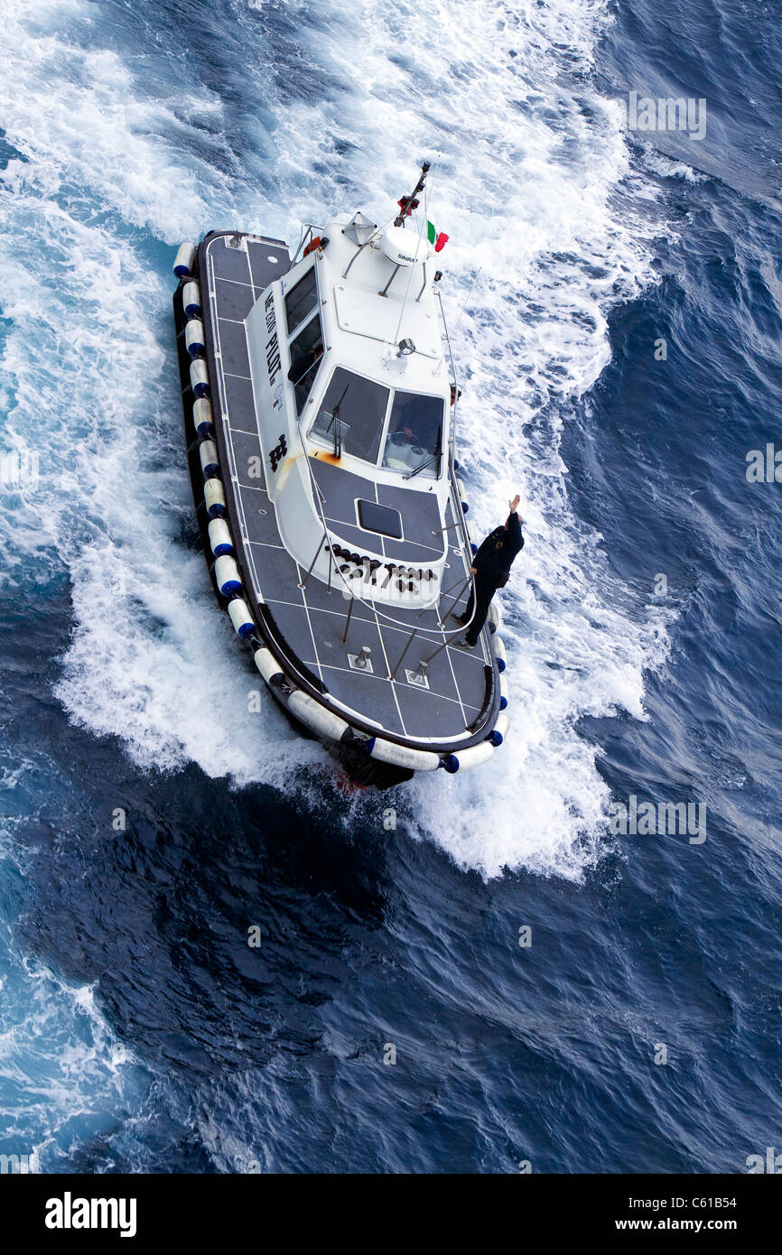 Barca pilota lungo il lato di una nave crociera lungo la costa del Mar Mediterraneo vicino a Messina Sicilia. Alta velocità e sicurezza costa navale. Foto Stock