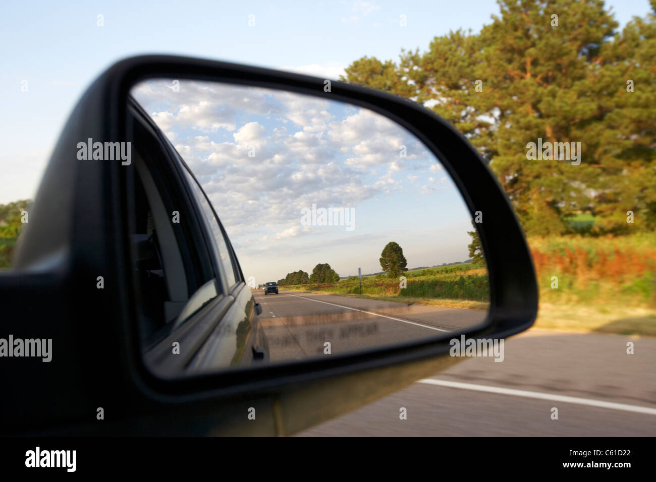 Ala auto specchio laterale che mostra cielo nuvoloso mentre si guida lungo una strada negli Stati Uniti Foto Stock