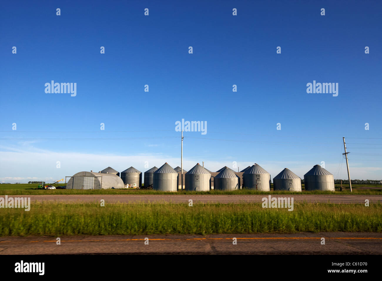 La guida passato silos per il grano su una superficie piana aperto farmland Dakota del Nord Stati Uniti d'America Foto Stock