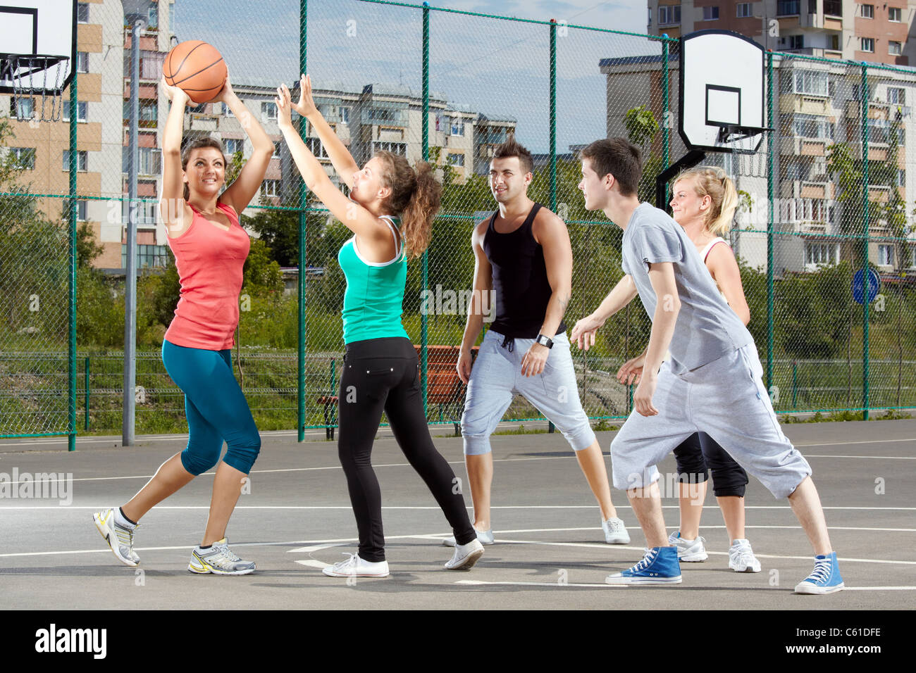 Giovani uomini e donne a giocare a basket in un parco Foto Stock