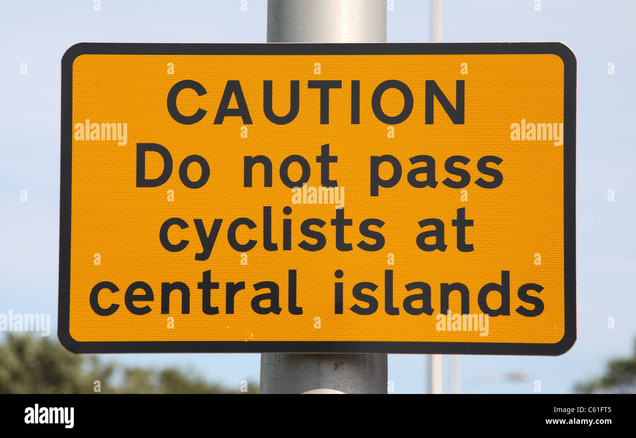 Cartello stradale attenzione agli automobilisti di non passare i ciclisti dove la carreggiata è limitato da un'isola centrale. Dunbar, Scozia. Foto Stock