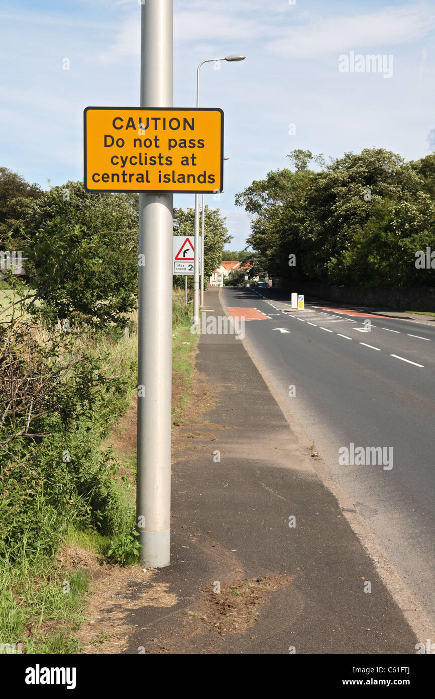 Cartello stradale attenzione agli automobilisti di non passare i ciclisti dove la carreggiata è limitato da un'isola centrale. Dunbar, Scozia. Foto Stock