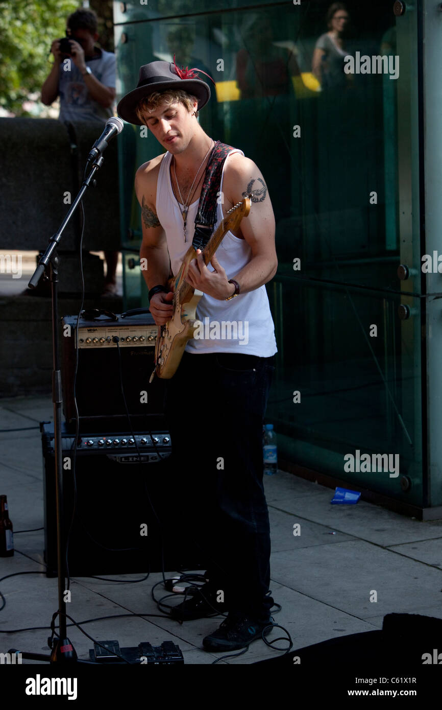 Ritratto a lunghezza intera di un busker maschile che suona una chitarra, Southbank, Londra, Inghilterra, Regno Unito. Foto Stock