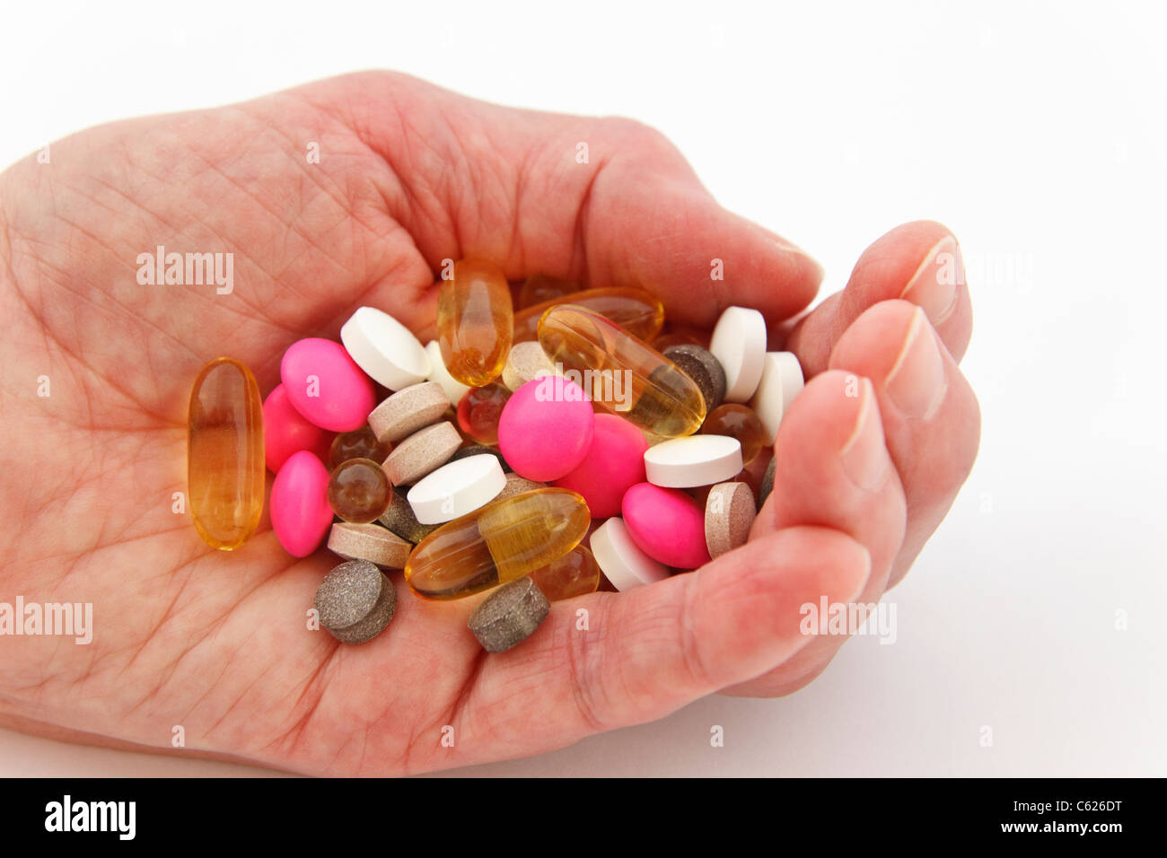 Donna anziana che tiene una selezione di differenti pillole di prescrizione e di supplemento nel palmo di una mano. Inghilterra Regno Unito Gran Bretagna Foto Stock