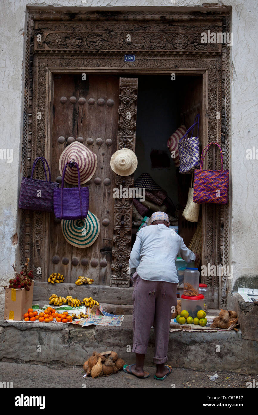 Un uomo locale al suo street negozio anteriore in Stone Town Zanzibar. Foto Stock