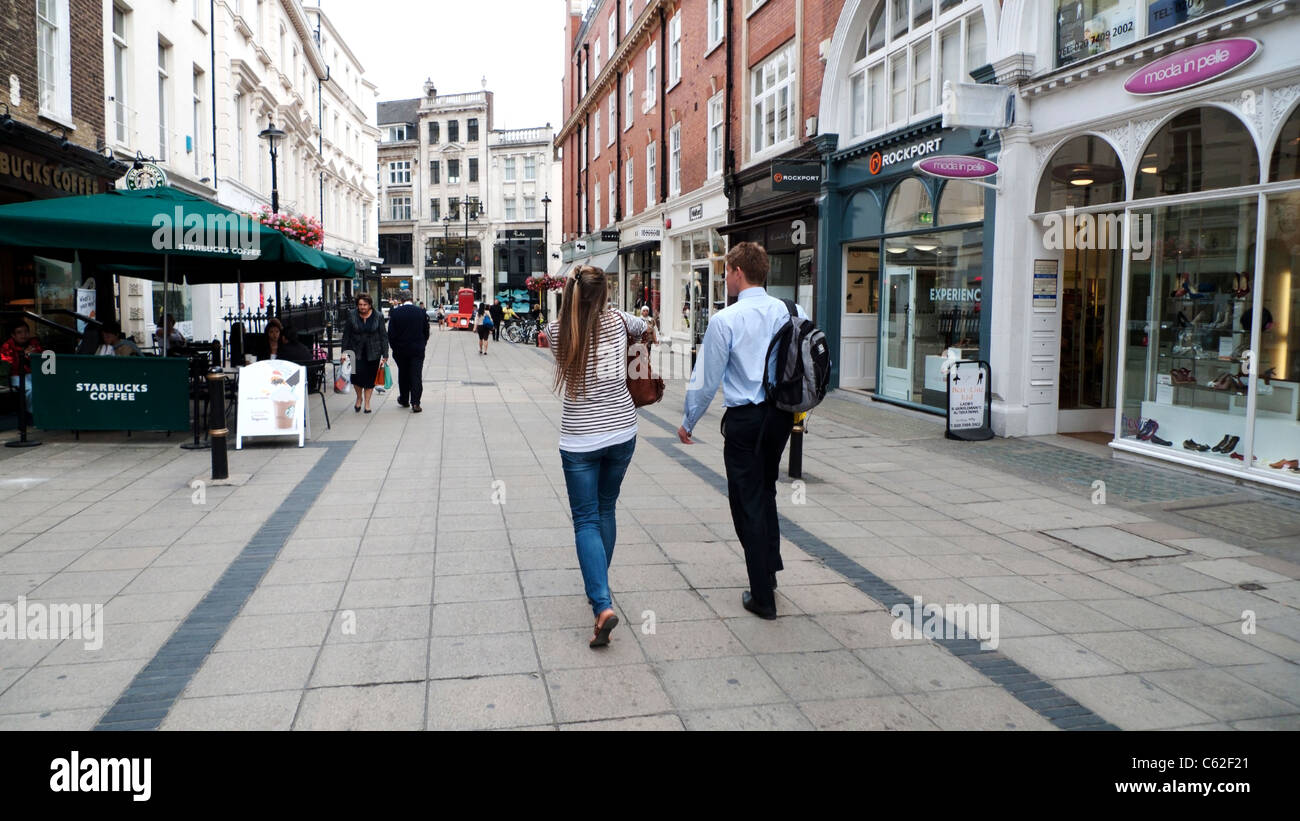 Una coppia giovane visto da dietro a piedi lungo passato negozi e boutique su New Bond street in London W1 Inghilterra UK KATHY DEWITT Foto Stock