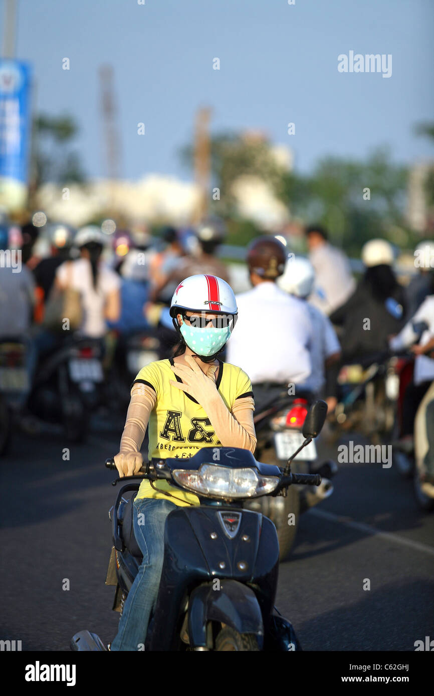 La donna corse in moto con la maschera per il viso e guanti lunghi in modo da mantenere la luce colorata della pelle. Foto Stock