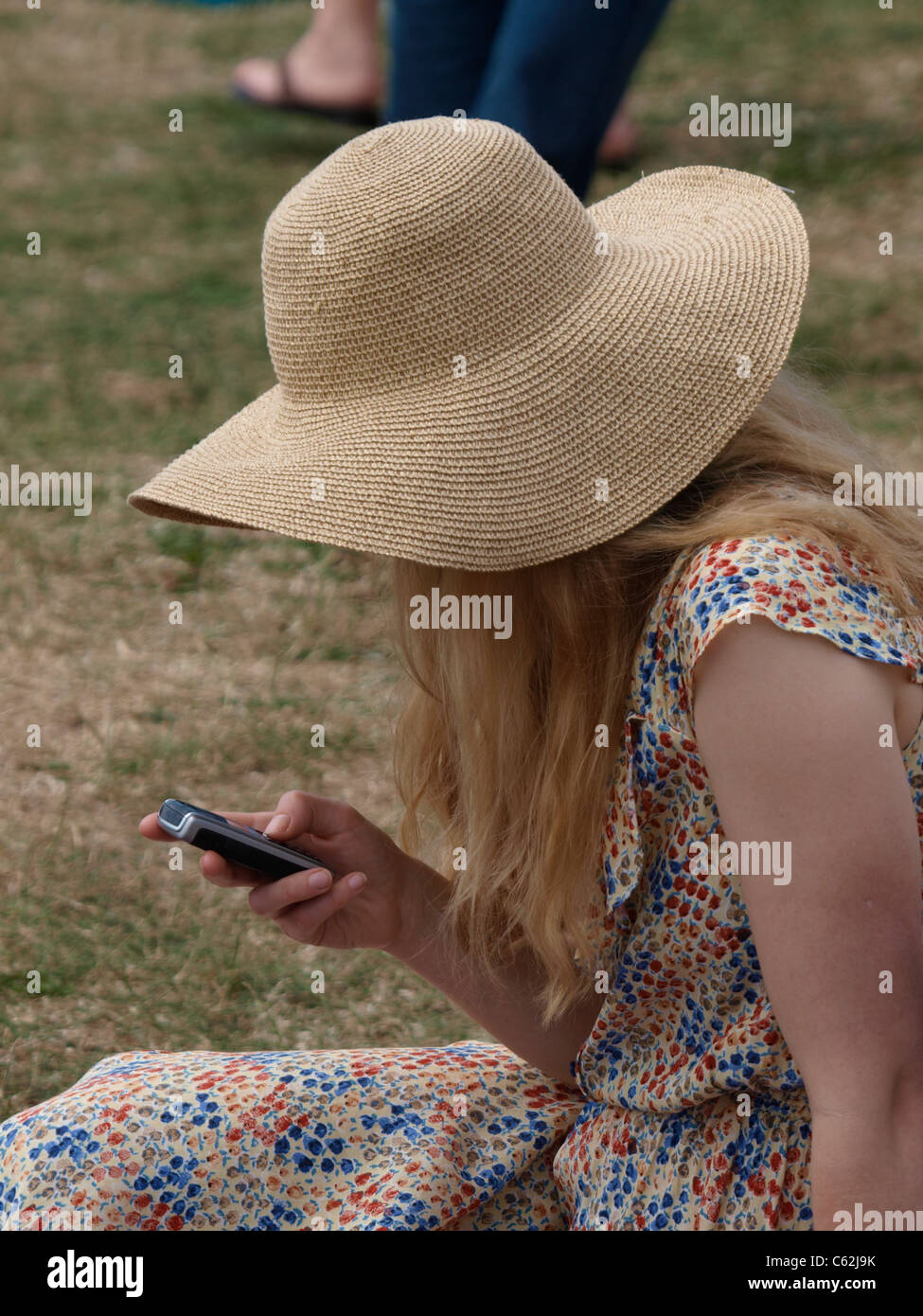 Giovane donna in un cappello di paglia texting, Devon, Regno Unito Foto Stock