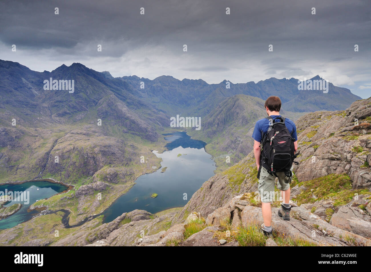 Walker ammirando la vista verso la Black Cuillin ridge sopra Loch Coruisk dal vertice di Sgurr na stri, Isola di Skye Foto Stock