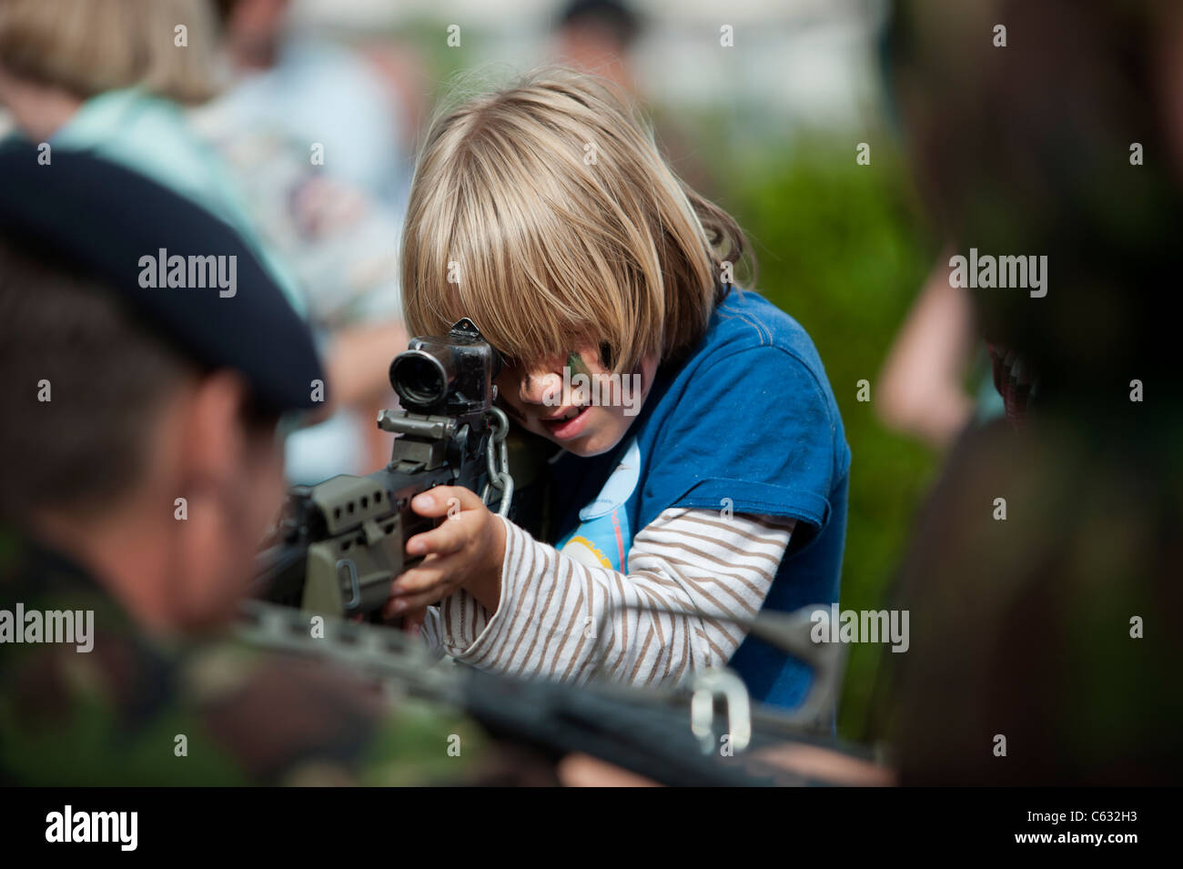 Un ragazzo in possesso di un fucile a un esercito stand fieristico. Eastbourne, East Sussex. Inghilterra, Regno Unito Foto Stock