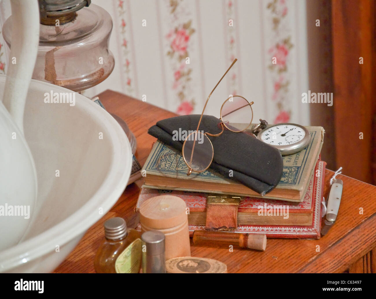 Questo stock immagine mostra vintage gli occhiali da lettura sulla parte superiore del retro libri, un orologio da tasca e altri articoli da toeletta oggetti antichi. Foto Stock