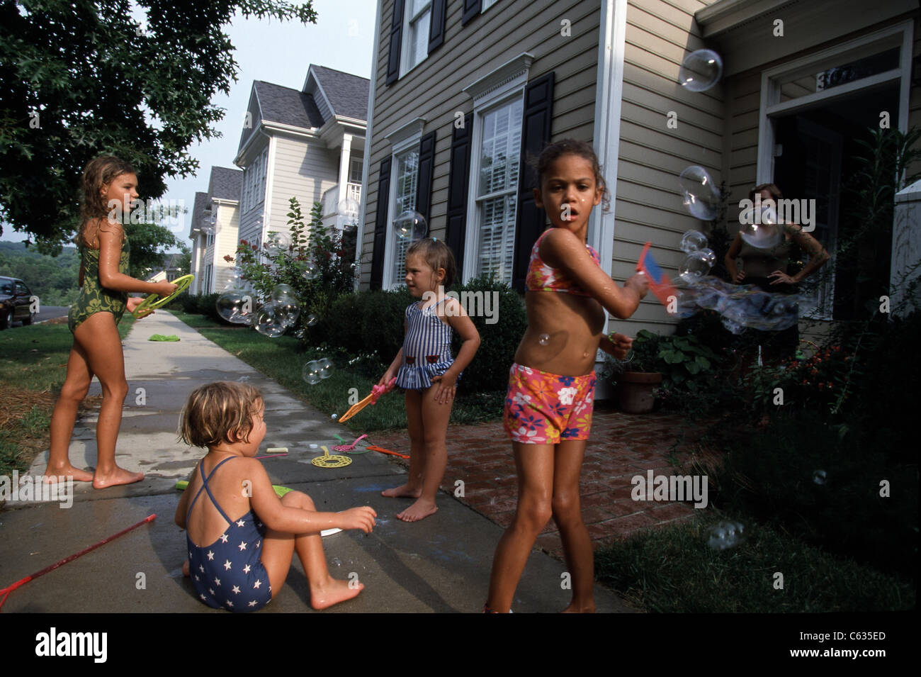 I bambini giocano nell'irrigatore al di fuori di una nuova costruzione townhouse complesso in Chapel Hill, North Carolina. Foto Stock