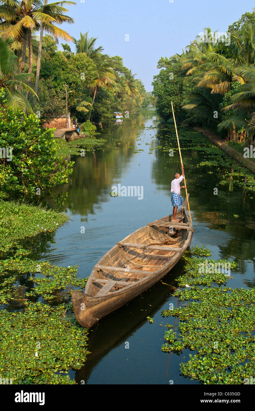 L'uomo punting canoa lungo Canal Backwaters Kerala India del Sud Foto Stock