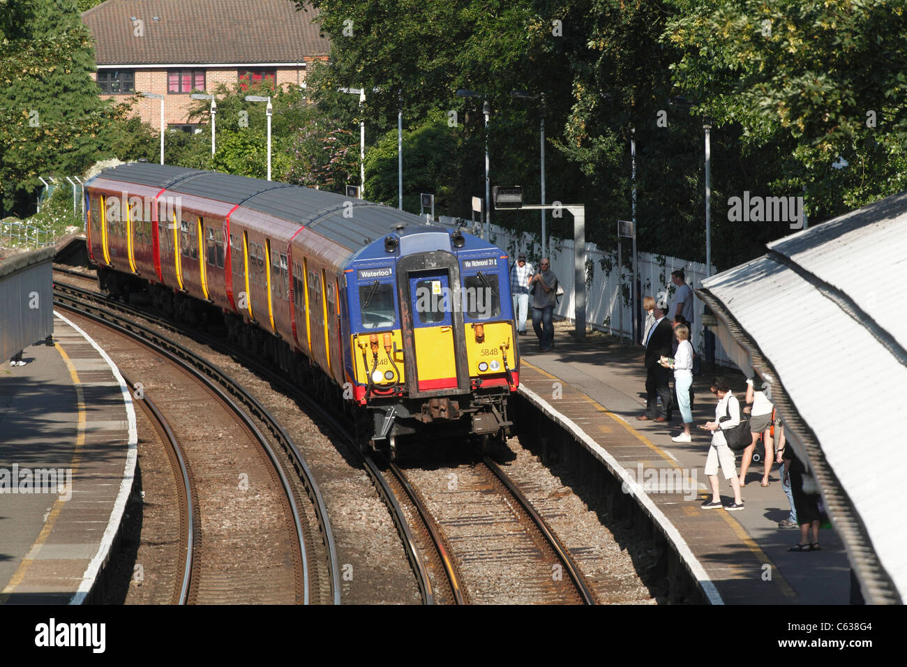 Il treno arriva a raccogliere i pendolari a west London station Foto Stock