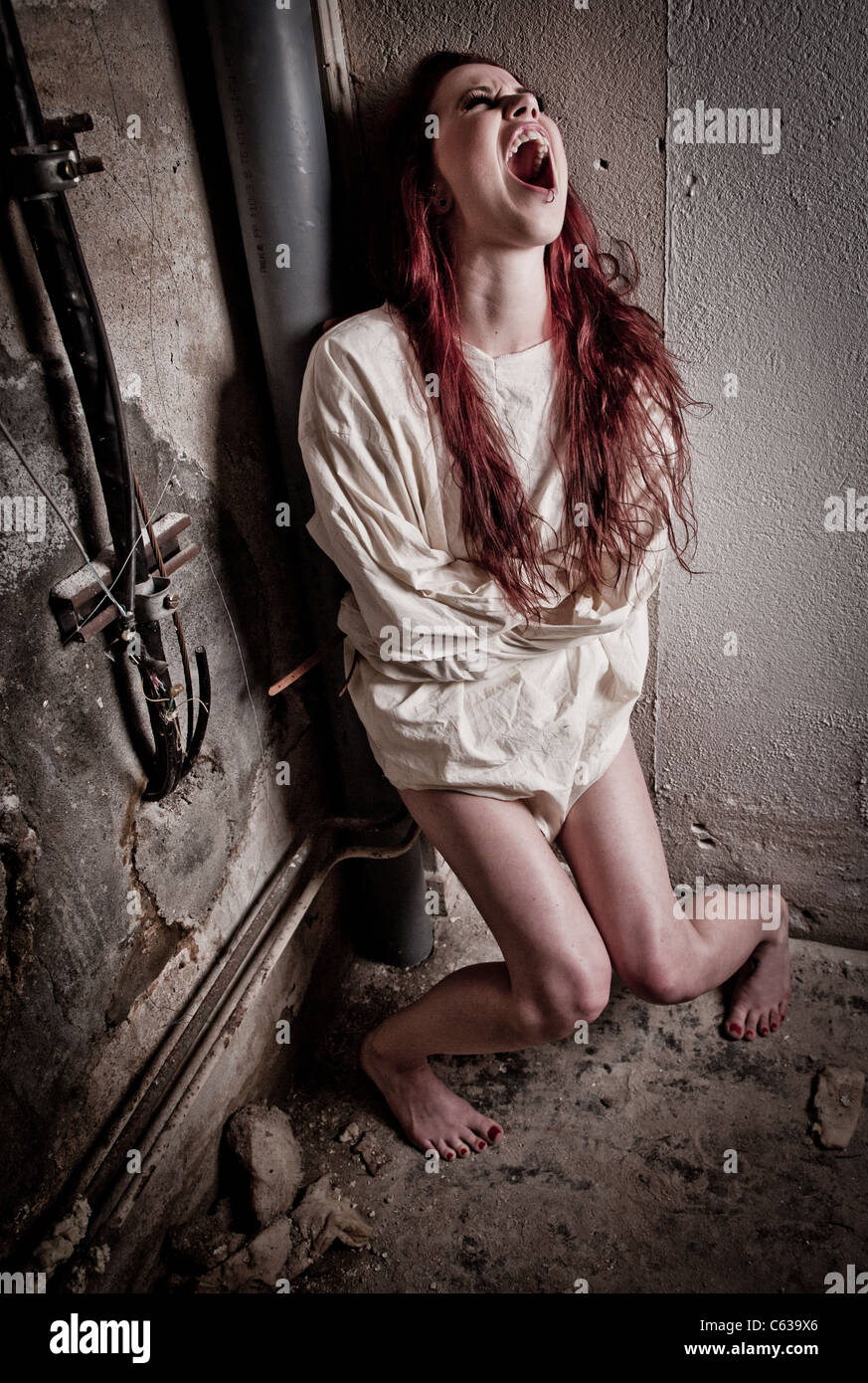 Un insano psico ragazza che indossa una camicia di forza Foto Stock
