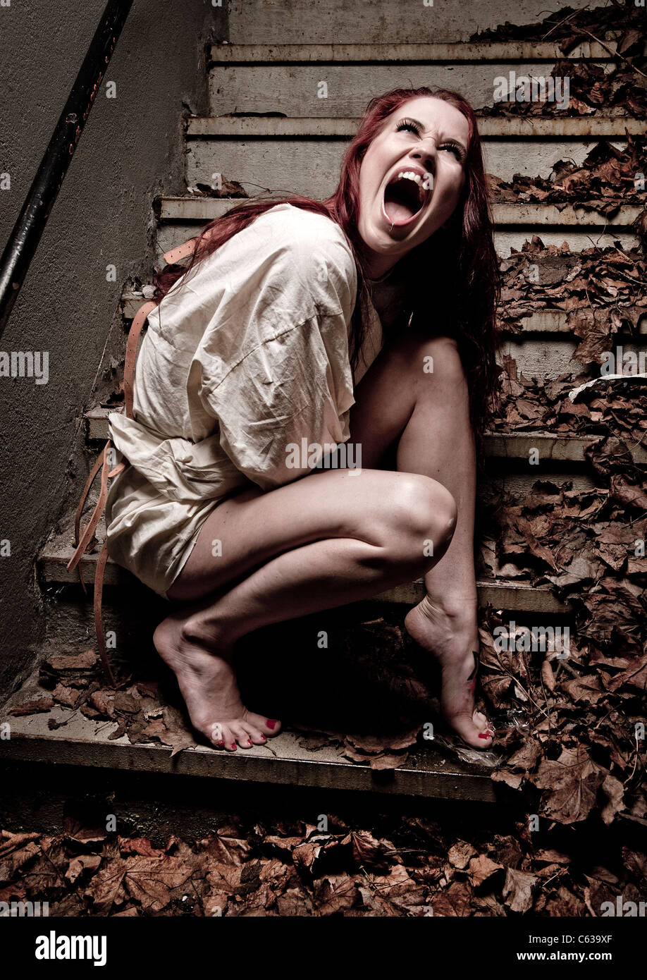 Un insano psico ragazza che indossa una camicia di forza Foto Stock