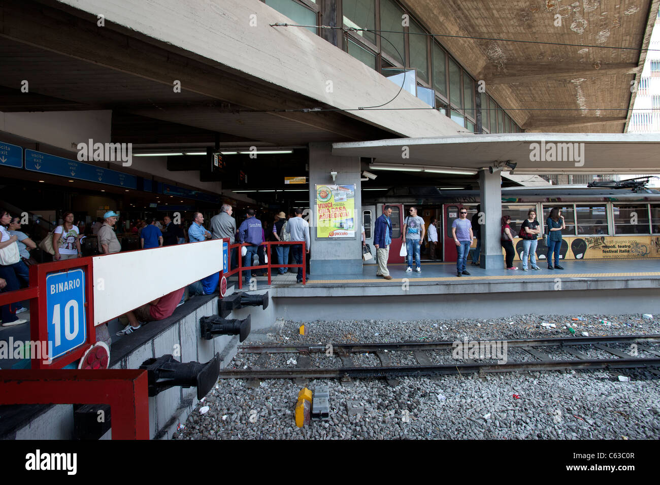 La stazione ferroviaria di Napoli, Italia mostra gli edifici moderni, con l'attesa la folla e i binari della ferrovia in primo piano. Foto Stock