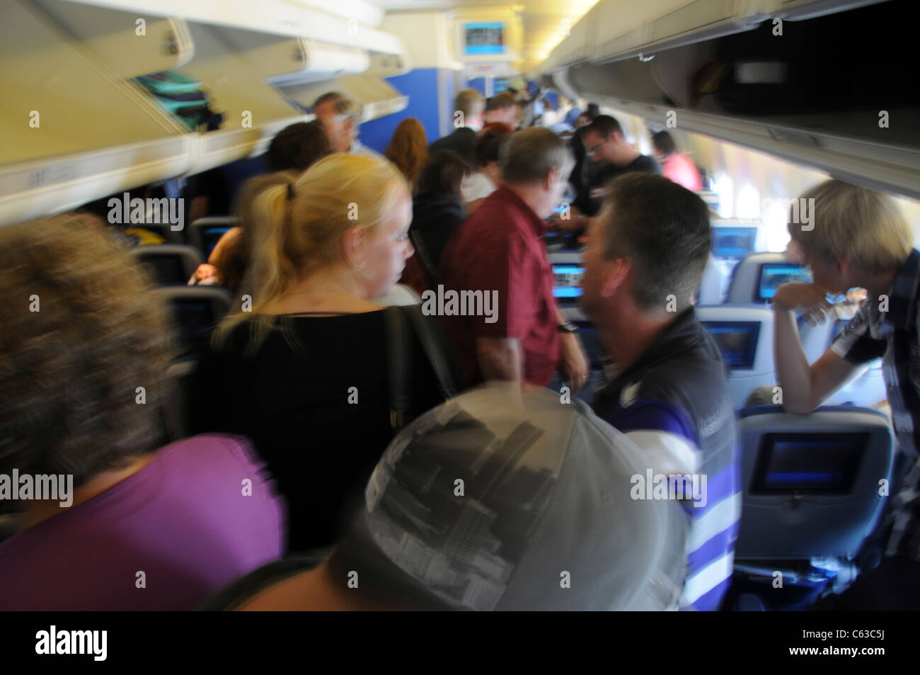 I passeggeri del trasporto aereo immissione o rimozione di trasportare il bagaglio dai compartimenti di overhead Foto Stock