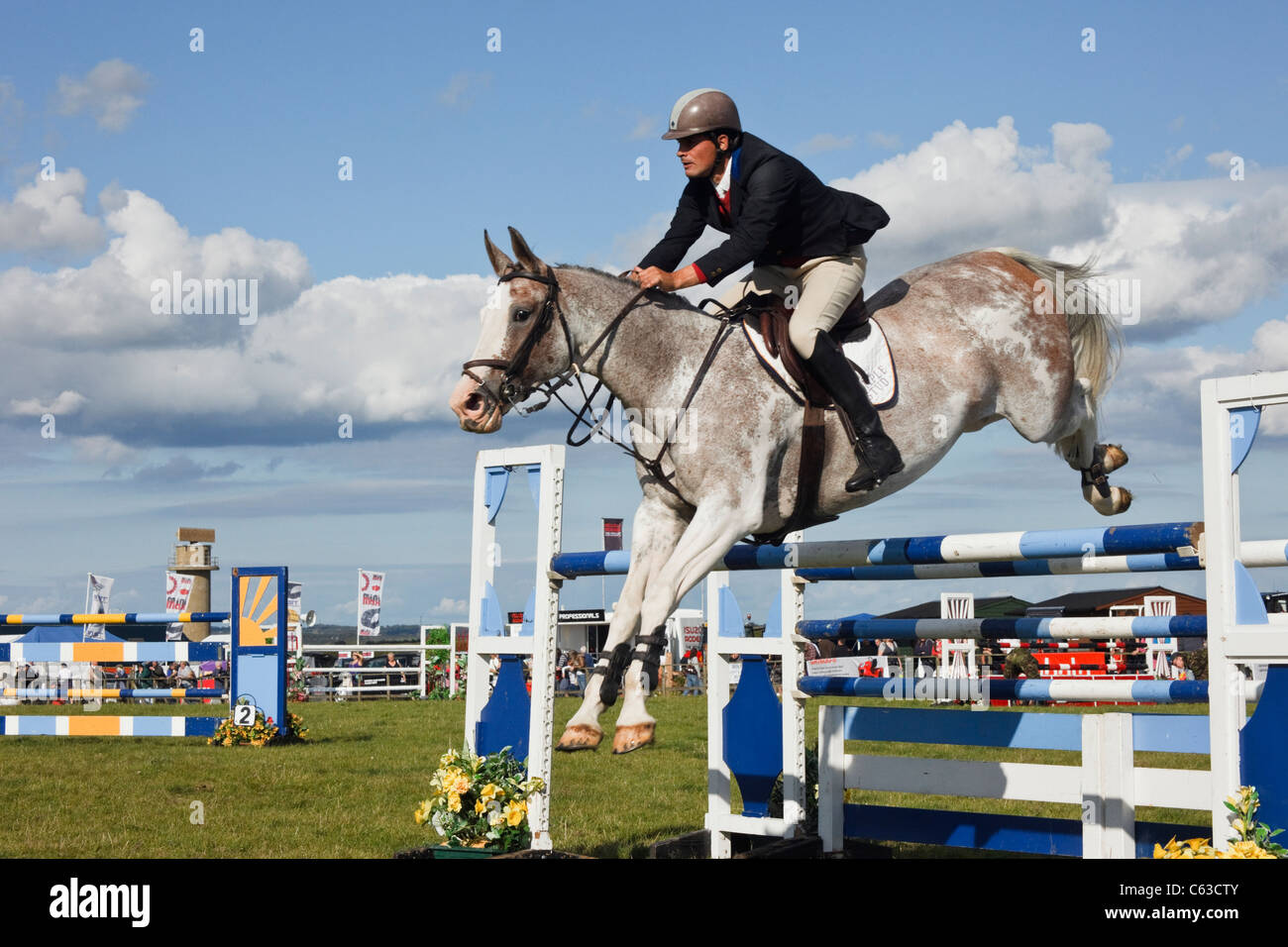 Evento internazionale di salto con cavalli e fantini che saltano su salti all'Anglesey Show in Mona showground. Galles del Nord, Regno Unito Foto Stock