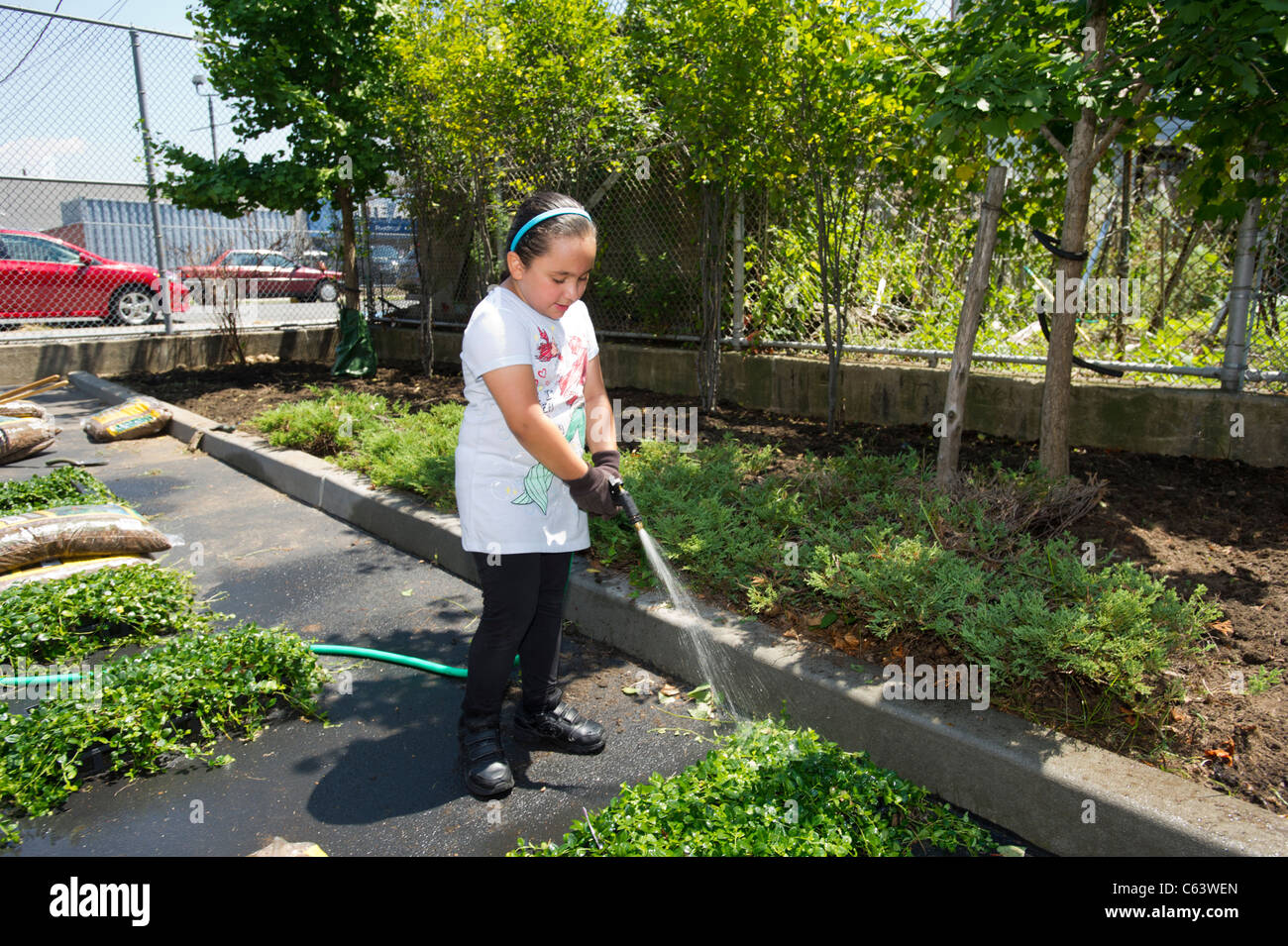 Gli studenti, la famiglia, gli amici e i volontari che partecipano in un giorno di lavoro in una scuola di New York Foto Stock
