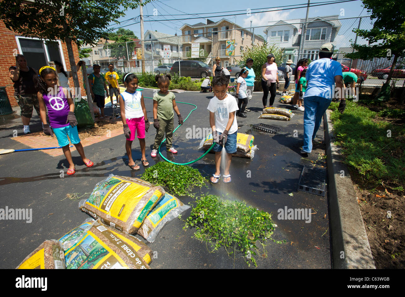 Gli studenti, la famiglia, gli amici e i volontari che partecipano in un giorno di lavoro in una scuola di New York Foto Stock