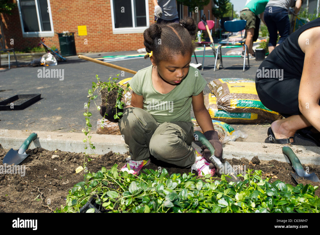 Gli studenti, la famiglia, gli amici e i volontari che partecipano in un giorno di lavoro in una scuola di New York Foto Stock