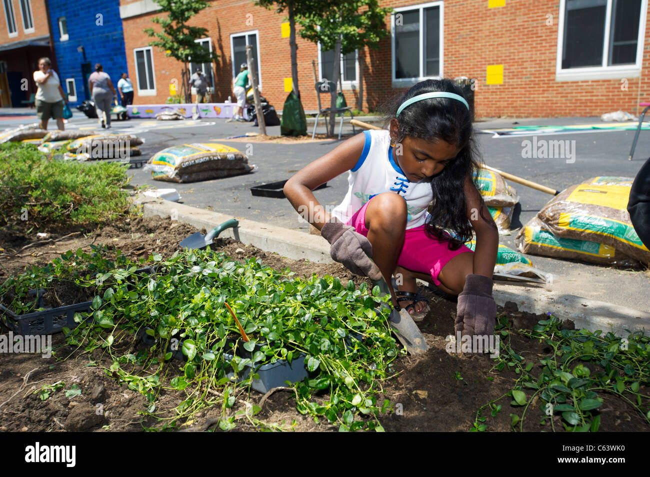Gli studenti, la famiglia, gli amici e i volontari che partecipano in un giorno di lavoro in una scuola di New York Foto Stock