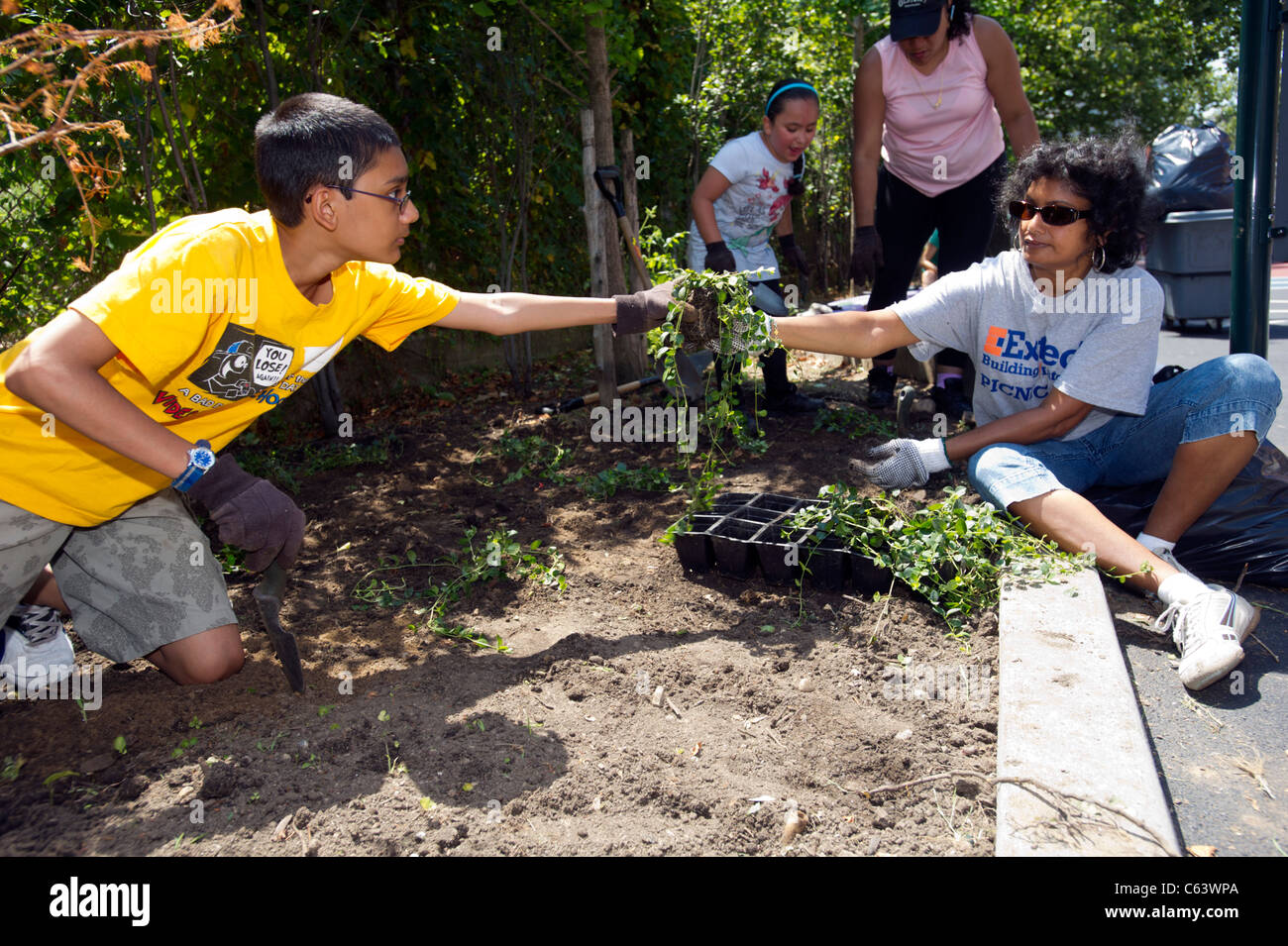 Gli studenti, la famiglia, gli amici e i volontari che partecipano in un giorno di lavoro in una scuola di New York Foto Stock