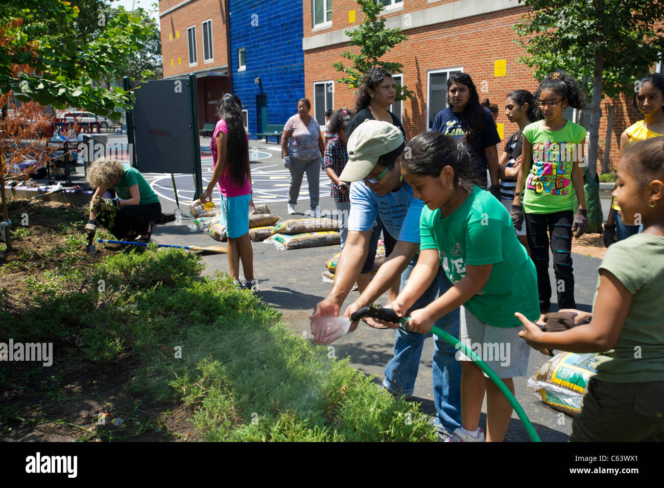 Gli studenti, la famiglia, gli amici e i volontari che partecipano in un giorno di lavoro in una scuola di New York Foto Stock