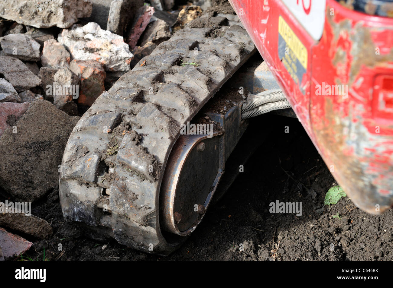 Dettaglio della gomma imbottito o continuo caterpillar traccia sulla piccola macchina di scavo Foto Stock