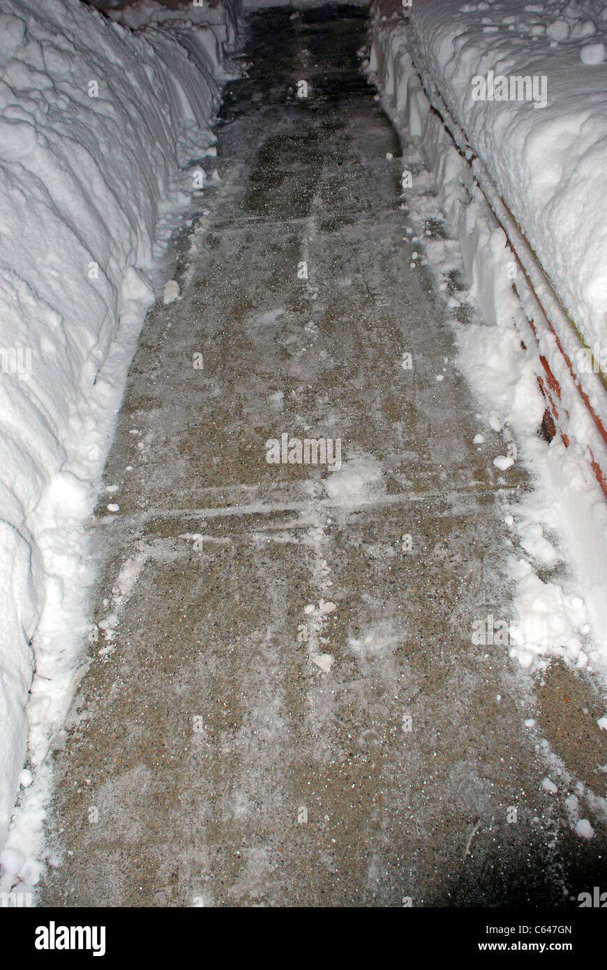 Shoveled marciapiede in profondo neve con particelle di fusione Foto Stock