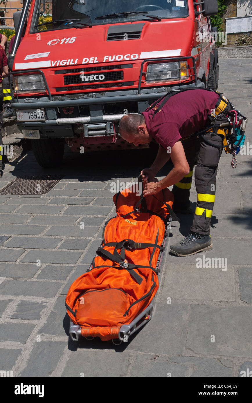 Un elemento maschio dei Vigili del Fuoco, una nazionale italiana di vigilanza antincendio corps prepara una barella su una strada di Vernazza, Italia. Foto Stock