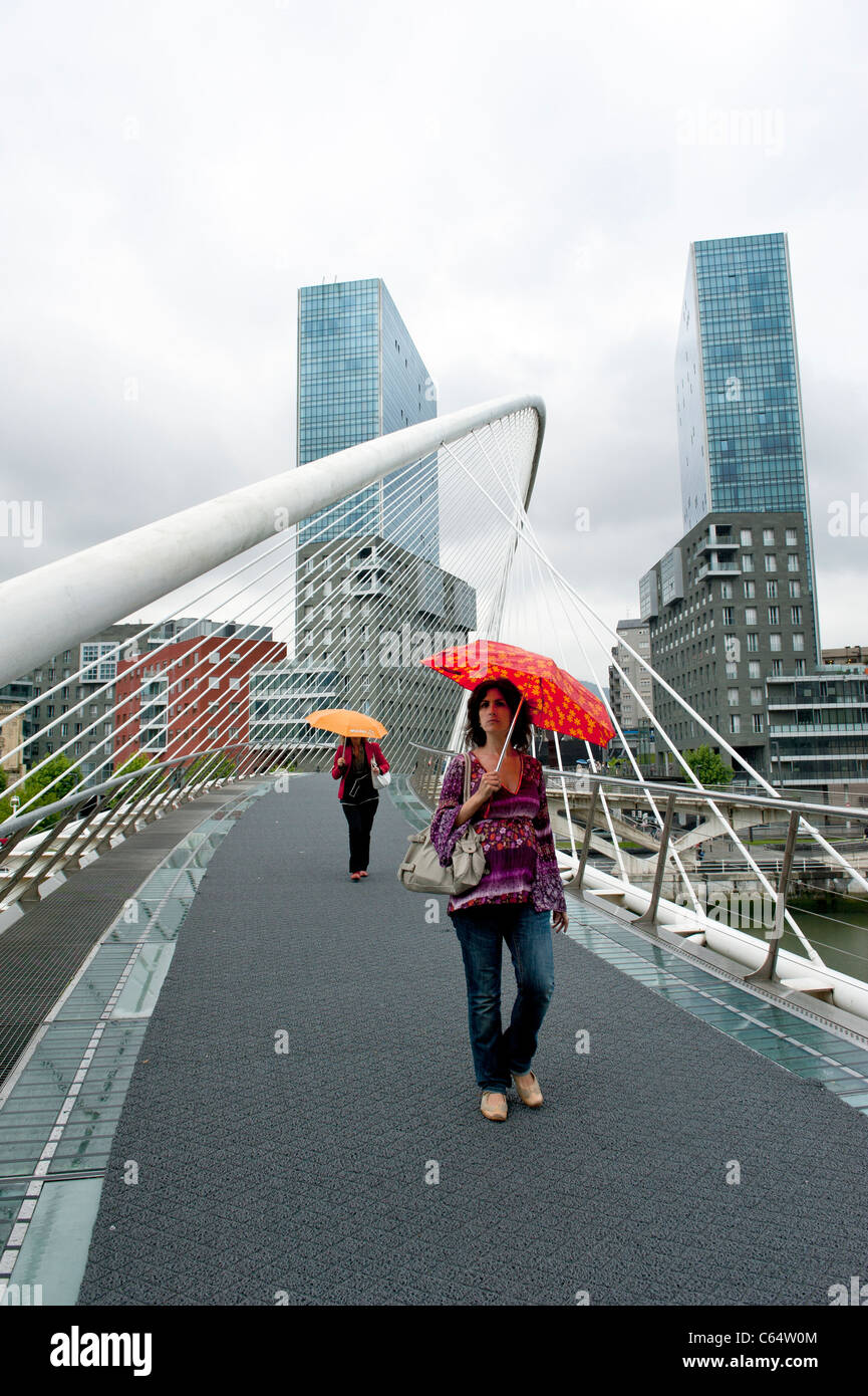Le donne che trasportano un ombrello su Santiago Calatrava del Ponte Zubizuri, Bilbao, nei Paesi Baschi della Spagna Foto Stock